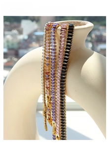 Detailed view of luxury gold tennis bracelets featuring multi-colored baguette-cut zircons