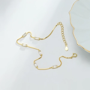 Detail shot of a 925 sterling silver gold box chain bracelet with emerald cut zircon stones