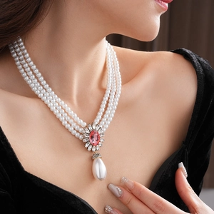 Gros plan détaillé d'un collier de perles à trois rangs avec pendentif fleur rose
