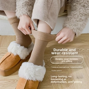 Close-up of thick knitted thermal crew socks in camel color paired with cozy plush slippers