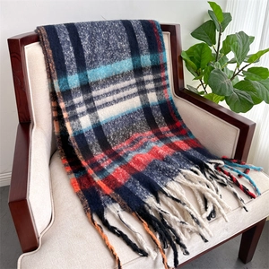 Detail of plaid scarf with tassels draped on a chair showing soft texture and fringes