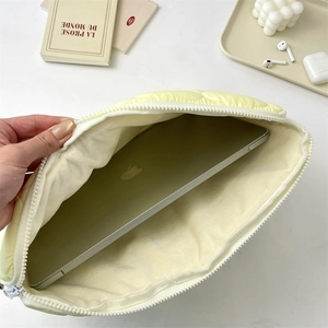 Detail view of the yellow quilted laptop sleeve showing soft off-white fleece lining