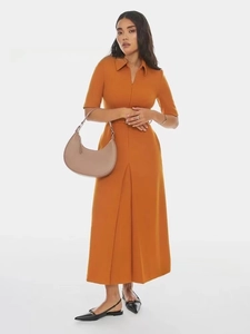 Chic beige crescent moon handbag styled with an orange dress on a model in a studio