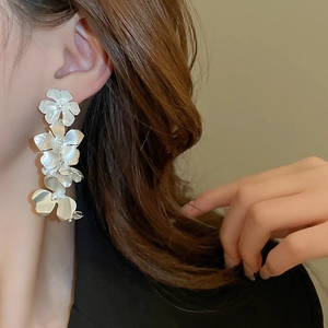 Detail of silver long floral drop earrings with matte petals and white bead centers