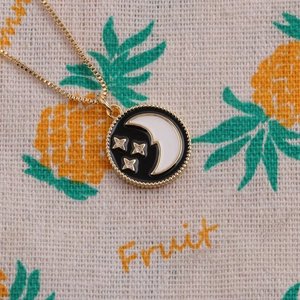 Golden moon and star pendant necklace with black enamel inlay and beaded edge detail