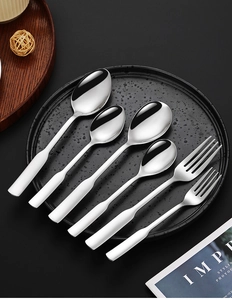 Close-up of polished 304 stainless steel spoons and forks on a black spotted plate