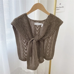 Brown knit cutout shawl wrap with tie-front knot design on a wooden hanger