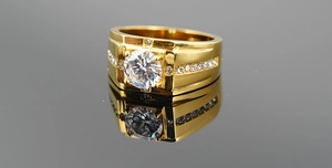 Macro shot of gold-plated wide band men's ring with a large center stone and pavé diamonds