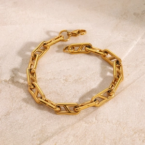 Elegant gold stainless steel bracelet with geometric hollow links on a white stone background