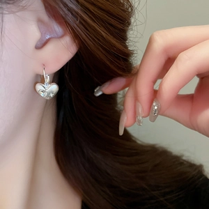 Macro shot of silver heart-shaped earring with star engraving and sparkling diamond