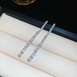 Gros plan de boucles d'oreilles pendantes avec zircons brillants et perles blanches