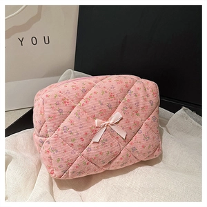 Detail of pink floral corduroy cosmetic bag with quilted texture and bow decoration