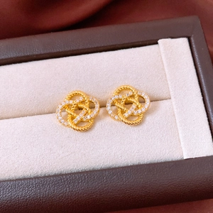 Macro shot of gold-plated twisted knot earrings with cubic zirconia on a leather box