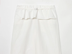 Détail du pantalon blanc avec taille volantée et ceinture fine à boucle métallique