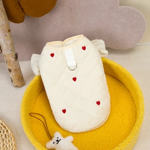 Detail of cream quilted pet vest with red heart embroidery and D-ring harness attachment