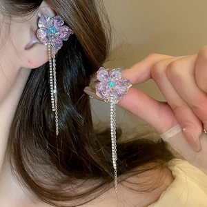 Close-up of sparkling purple flower earrings with blue zircon and long silver tassels