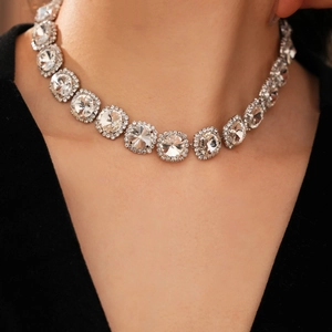 Close-up of sparkling diamond necklace with round tassel pendant on a model's neck