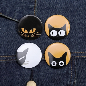 Set of four minimalist round cat tinplate badges pinned on dark blue denim fabric