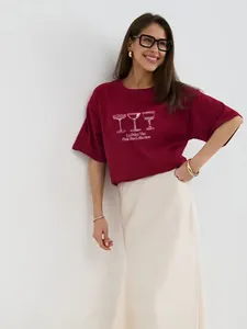 Λεπτομέρεια από μπορντό βαμβακερό T-shirt με τύπωμα και κρεμ midi φούστα σύνολο