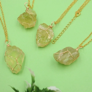 Detailed flat lay of four handmade wire wrapped light green natural crystal stone necklaces