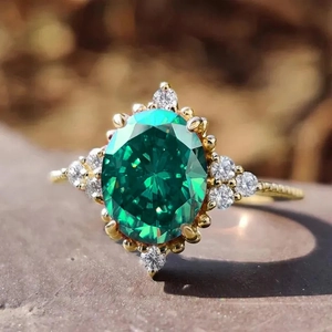 Macro shot of gold ring with emerald oval gemstone and shimmering diamond accents