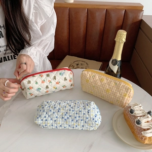 Detailed view of three quilted floral pencil cases in blue, yellow, and white cotton fabric