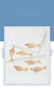 Detail of colorful evil eye fishbone pendants in gold-plated alloy for DIY jewelry making