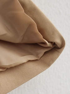 Nahaufnahme eines khakifarbenen Trenchcoats mit Twill-Gewebe und seidigem Innenfutter