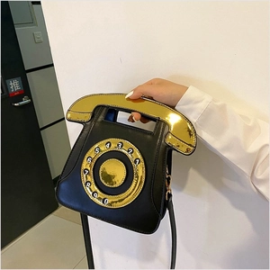 Detail of vintage telephone handbag featuring a golden handset handle and rotary dial