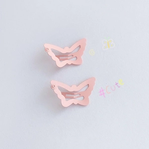 Close-up of two pieces of matte pink butterfly-shaped hollow hair clips for girls