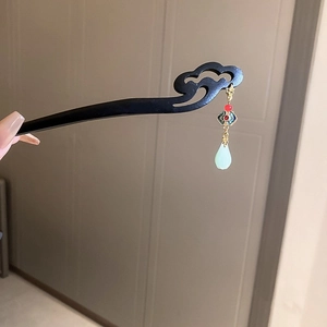 Detail of wooden hair stick with red bead and light green teardrop pendant