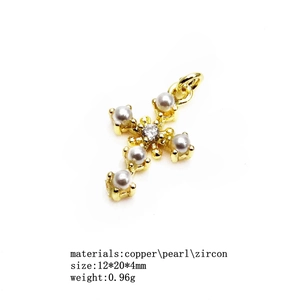 Macro view of golden copper cross pendant with small white pearls and clear zircon