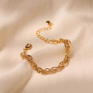 Thick gold-plated twisted chain bracelet with lobster clasp on beige fabric background