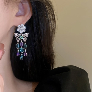 Primo piano di orecchini a nappa in argento con zirconi colorati indossati da una modella