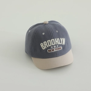 Detail of grey-blue corduroy kids cap with embroidered BROOKLYN letters and beige brim