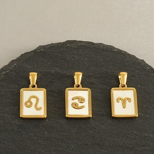 Detail view of gold zodiac pendants with white shell inlay on black slate