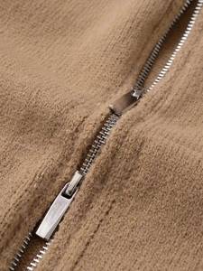 Macro detail of camel knit fabric featuring a high-quality silver metal zipper closure