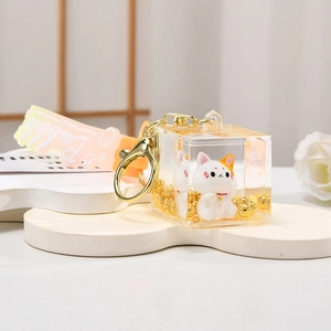 Detail view of the liquid quicksand lucky cat keychain with golden beads and bubble wrist strap