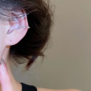 Detailed close-up of a gold geometric ear cuff set with crystals on a woman's ear