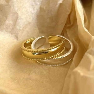 Detailed view of silver and gold open rings with beaded edges on yellow paper