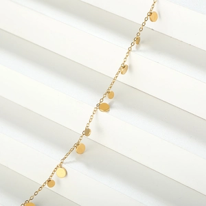 Macro shot of gold plated stainless steel chain featuring polished round disc pendants