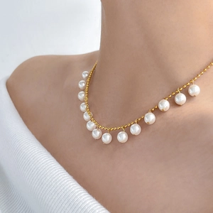 Detail view of a double-layer gold snake chain necklace with pearls and butterfly tassel