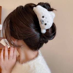 Detail of white plush bear hair claw clip on model's hair for a cute winter look