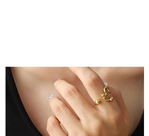 Vue détaillée d'une bague géométrique dorée ouverte aux lignes abstraites sur le doigt