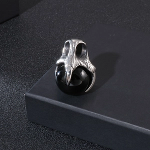 Detail of punk style dragon claw pendant holding a black gemstone in polished silver finish