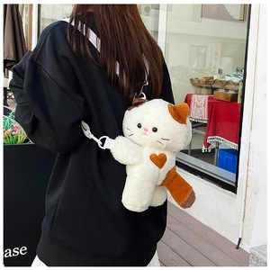 Detail view of a cute plush calico cat crossbody bag with white straps and brown heart