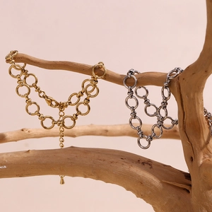 Detail of gold and silver layered chain anklets hanging on a natural wood branch background