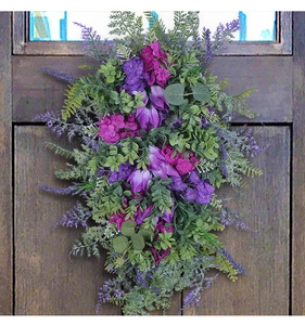 Spring purple tulip wreath with green ferns hanging on a dark brown wooden door