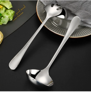 Detail view of SUS 304 gold stainless steel soup ladle and slotted spoon on a grey plate
