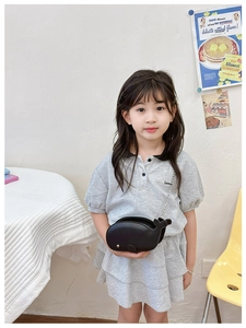 Toddler girl wearing a black whale-shaped crossbody bag with a sleek chain strap